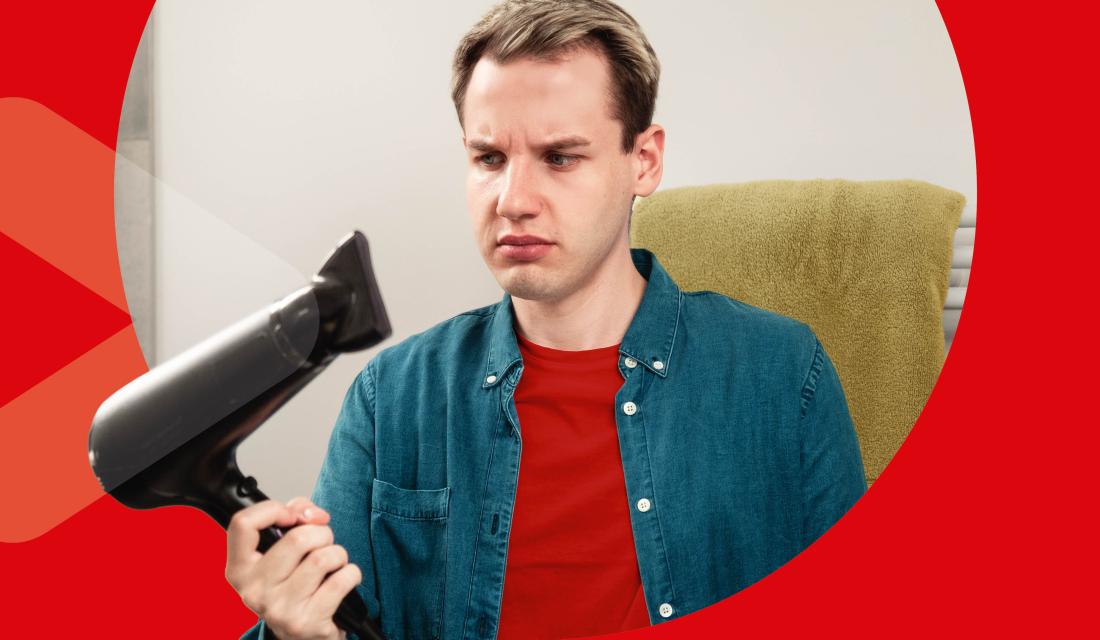 junger Mann guckt skeptisch auf Föhn