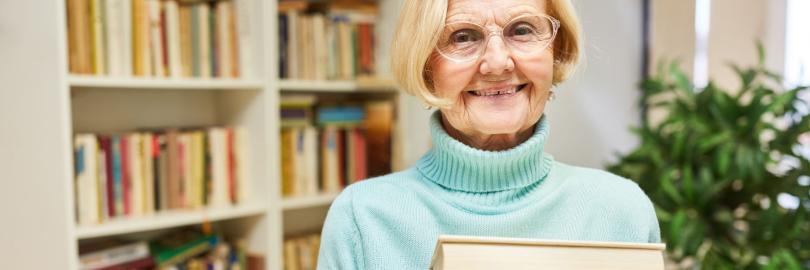 Rentnerin mit einem Stapel Bücher im Arm