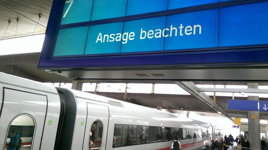 Ein ICE steht an einem Bahnhofsgleis mit der Anzeige "Ansage beachten"