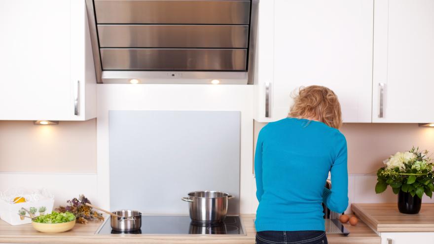 Eine Frau steht vor einer Dunstabzugshaube in der Küche