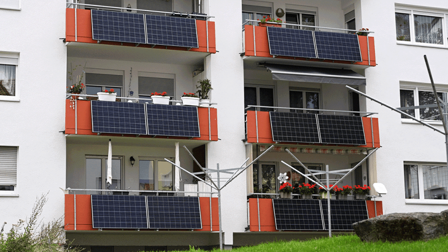 Hausfront mit mehreren Balkonen mit Steckersolarmodulen