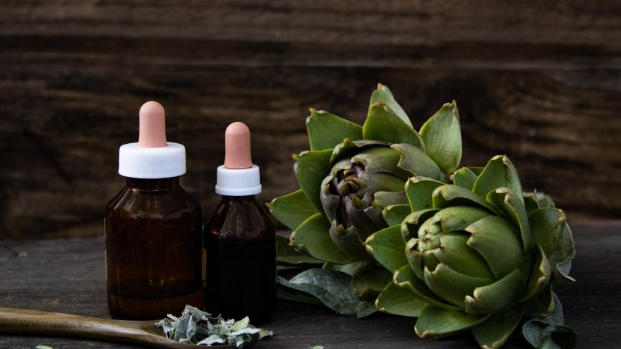 Artischocken, daneben zwei Fläschchen mit einer Tinktur