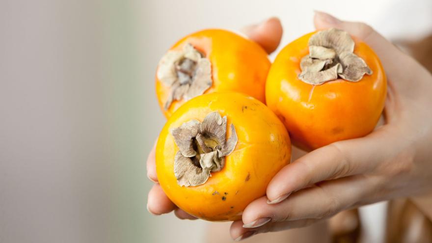 Kaki - süßes Obst für den Winter: Hände halten drei Kakis