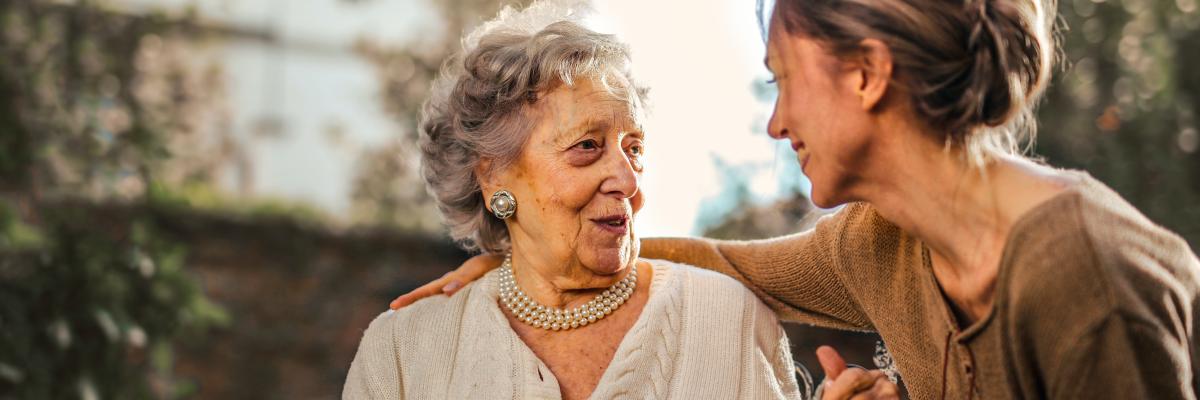 eine ältere und eine jüngere Frau sitzen im Garten und reden