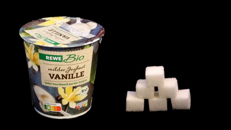 Joghurtbecher von Rewe Bio Vanille und daneben eine Zuckerwürfel-Pyramide