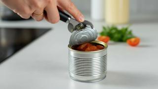 Eine Hand mit Dosenöffner über einer geöffneten Konservendose